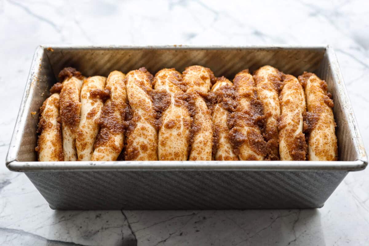 Irresistible Cinnamon Pull-Apart Bread is inspired by the popular cinnamon bread served at the Grist Mill eatery in Dollywood. With this copycat version, you can recreate that buttery, sweet deliciousness easily with frozen rolls. Overhead shot of the cinnamon pull-apart bread rising in the loaf pan.