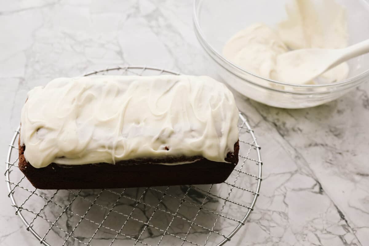 Starbucks copycat gingerbread loaf is the ultimate holiday treat! It's coated in a simple cream cheese frosting and is full of warm spices and rich molasses flavor. Enjoy it for Christmas brunch or a sweet treat at night! Overhead shot of the frosting spread over the top of the loaf.