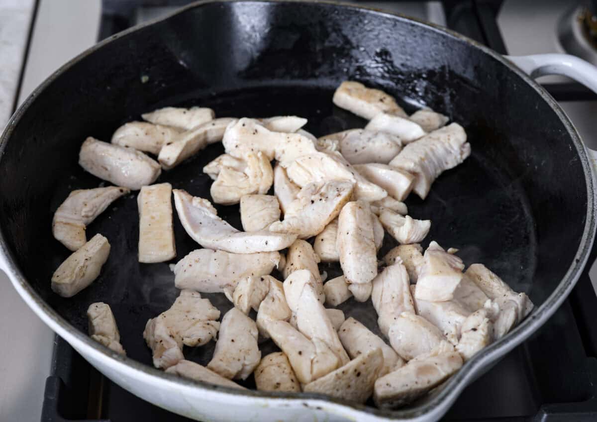 Moo Shu Chicken is a takeout favorite that’s so easy to make at home! This flavorful dish combines tender strips of chicken, mushrooms, and cabbage with a sweet and savory sauce. It’s quick, packed with vibrant flavors, and the perfect weeknight meal! Angle shot of chicken being cooked in a skillet.