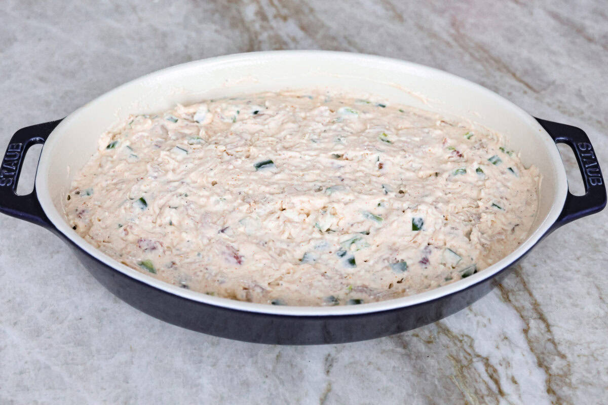Spice up dinnertime with this creamy Jalapeño Popper Casserole! Packed with tender chicken, melty cheese, and just the right kick of heat, it's hearty and so easy to make. Delicious comfort food with a spicy twist! Angle shot of the chicken and cream cheese mixture spread into the bottom of a baking dish.