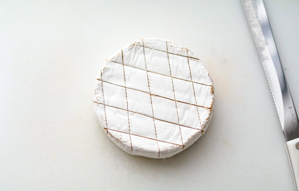 Warm and gooey baked brie is a hit for any occasion! With just five simple ingredients and less than 20 minutes, you will have a rich, creamy appetizer that's impossible to resist. Scoop it up with your favorite crackers or bread! Overhead shot of a circle of brie cheese with diamond slices in the top.