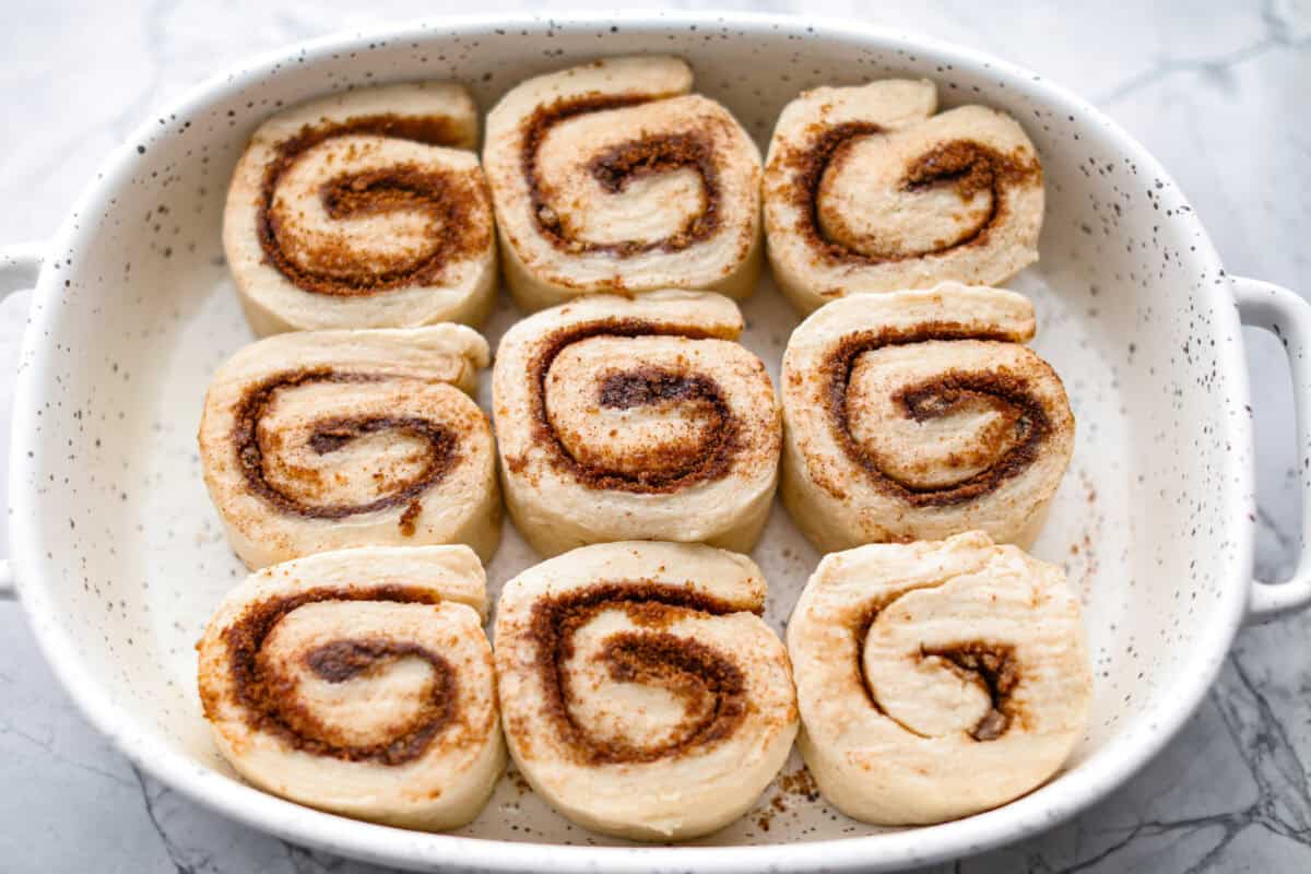 Biscuit Cinnamon Rolls are the most amazing twist on a classic! They are perfectly light, fluffy, and packed with cinnamon. The texture is more flakey and moist than traditional cinnamon rolls! Whether it’s for a cozy weekend breakfast or a holiday brunch, these hit the spot! Overhead shot of biscuit cinnamon rolls on their side in baking dish.