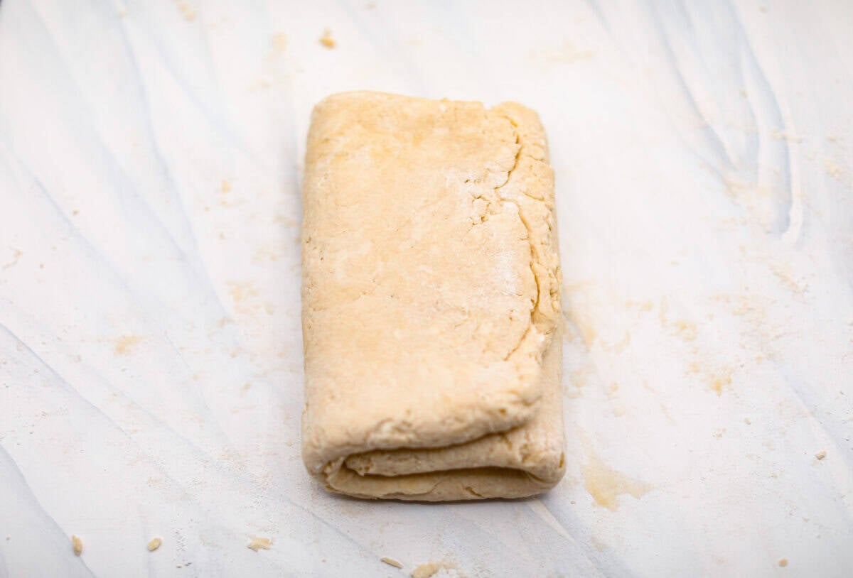 Biscuit Cinnamon Rolls are the most amazing twist on a classic! They are perfectly light, fluffy, and packed with cinnamon. The texture is more flakey and moist than traditional cinnamon rolls! Whether it’s for a cozy weekend breakfast or a holiday brunch, these hit the spot! Overhead shot of biscuit dough folded into a tri-fold.