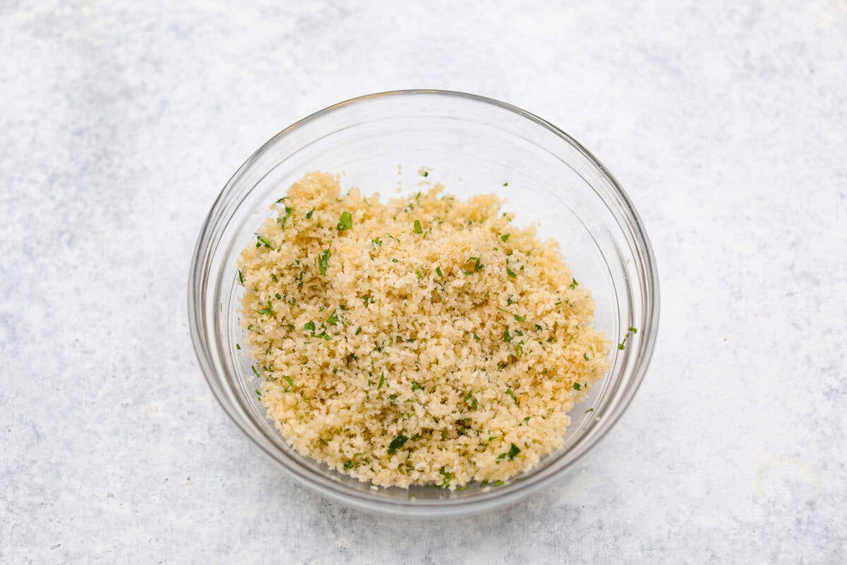 Boursin stuffed mushrooms are a fun, delicious appetizer or side dish. These creamy, cheesy stuffed mushrooms are packed with flavorful Boursin cheese and topped with a delightful breadcrumb crunch. Overhead shot of a bowl with bread crumbs, parsley and butter mixed together.