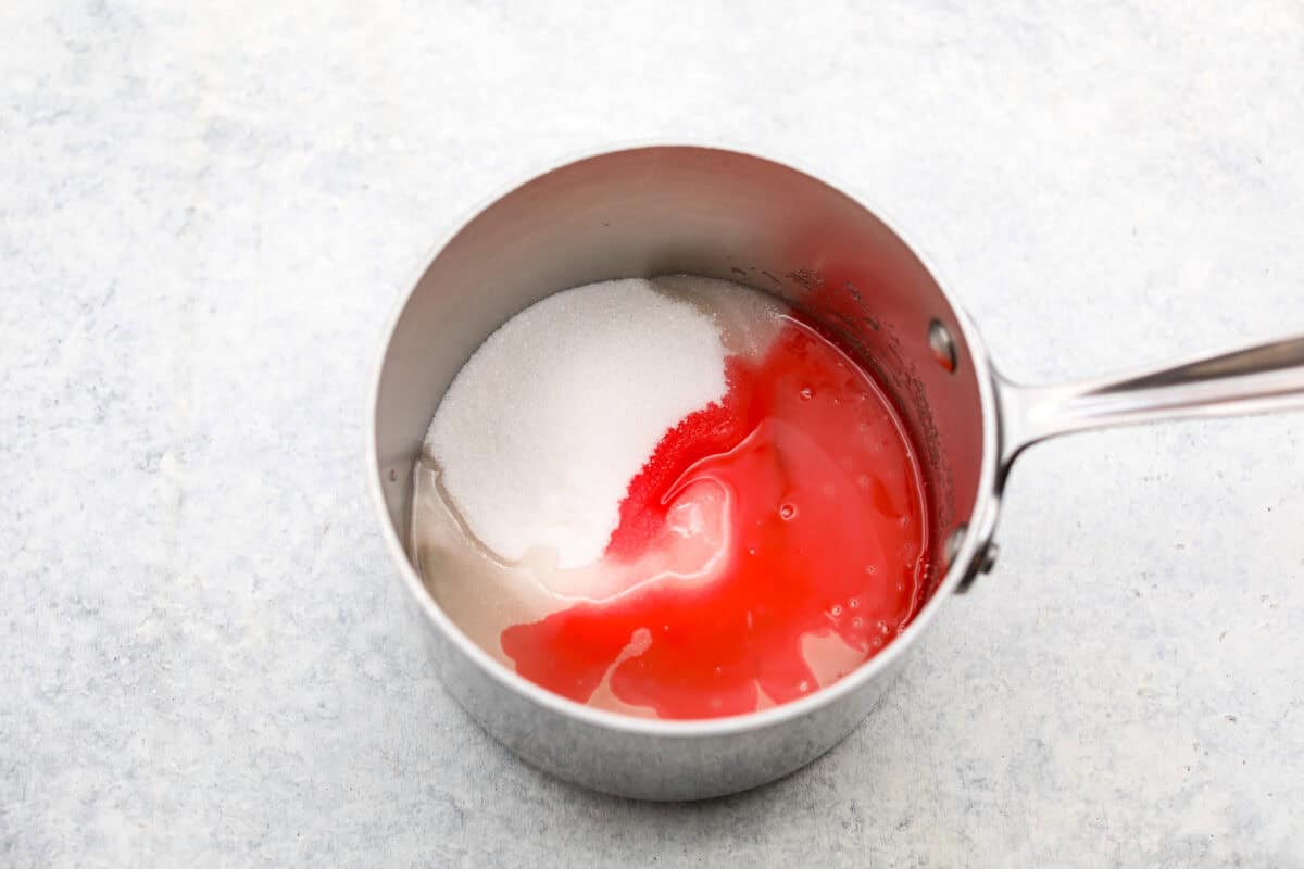 Homemade cherry cordials are a tasty, nostalgic treat! They're made with sweet cherries that are coated in a rich chocolate shell. Make them for Christmas or Valentineโs Day, and watch them disappear! Overhead shot of sugar, water corn syrup and maraschino liquid in a saucepan.