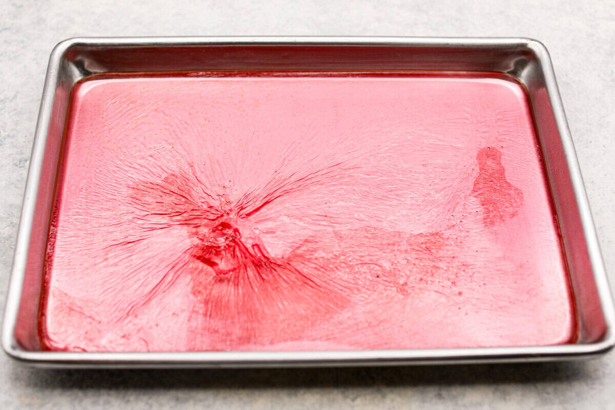 Homemade cherry cordials are a tasty, nostalgic treat! They're made with sweet cherries that are coated in a rich chocolate shell. Make them for Christmas or Valentineโs Day, and watch them disappear! Overhead shot of syrup cooling on a baking sheet.