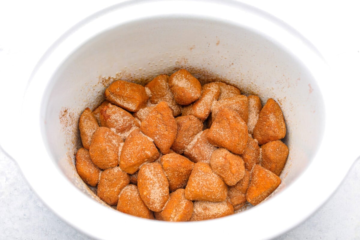 Crockpot monkey bread is an easy, gooey treat made in your slow cooker. It’s packed with soft biscuit pieces, cinnamon-sugar flavor, and a sweet buttery glaze. No oven needed! Overhead shot of cinnamon sugar biscuit dough in the bottom of the crock pot.