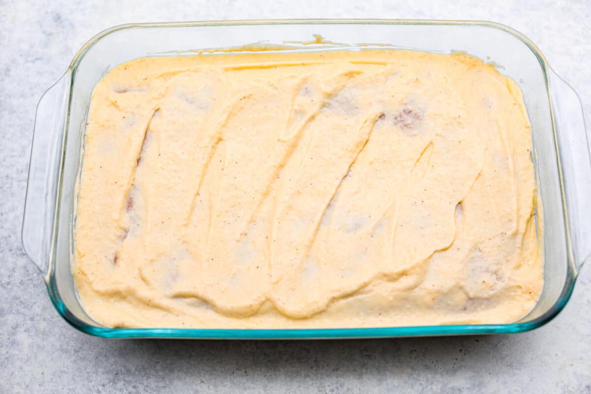 Eggnog Poke Cake could not be more perfect for the holiday season! It combines the rich flavor of eggnog with the soft, moist texture of a classic poke cake. Add fluffy whipped topping and a sprinkle of nutmeg and cinnamon to really wow your family! Overhead shot of the cake topped with the topping.