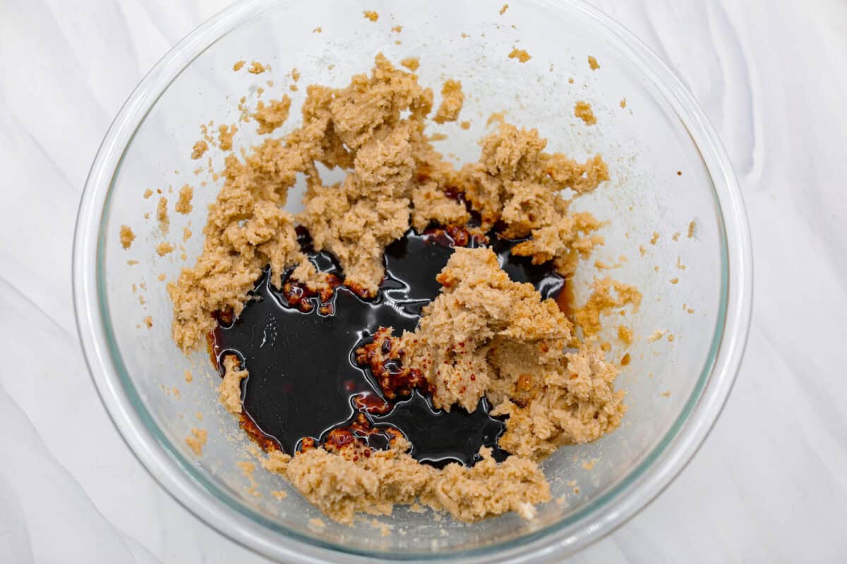 These gingerbread crinkle cookies are incredibly soft and flavorful! Their deep molasses flavor, spiced to perfection and rolled in powdered sugar, is so good with a glass of milk. They are the perfect cookies to make for Santa this holiday season. Overhead shot of creamed butter and sugar with molasses added.