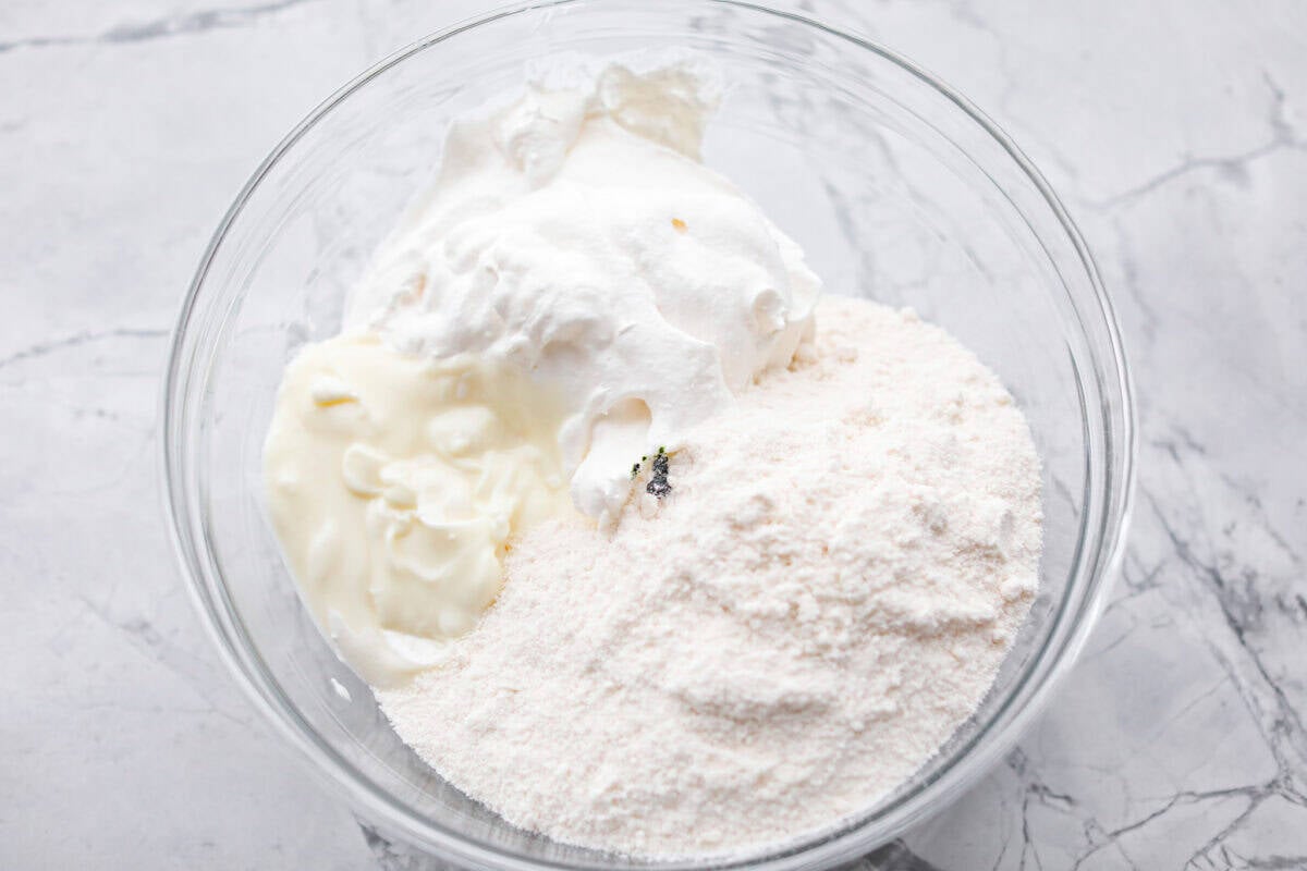 Grinch dip is a sweet and scrumptious dip perfect for any holiday party or gathering. It combines delicious cake mix, fluffy whipped topping, and smooth yogurt or pudding to create a fun dip for cookies, treats, or fruit. Overhead shot of Grinch dip ingredients in a mixing bowl.