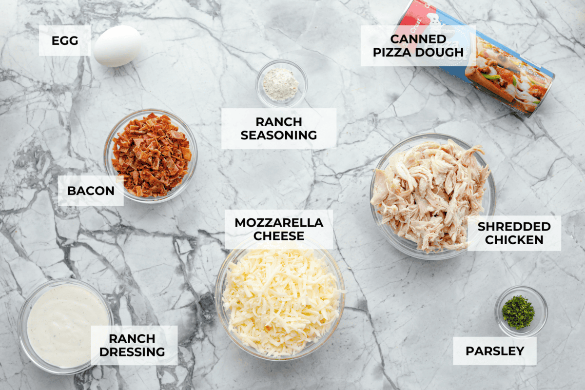 This Chicken Bacon Ranch Stromboli combines the tasty trio of tender chicken, crispy bacon, and creamy ranch dressing, all wrapped in golden pizza dough. It’s quick to prep and packed with flavor. Overhead shot of labeled ingredients.