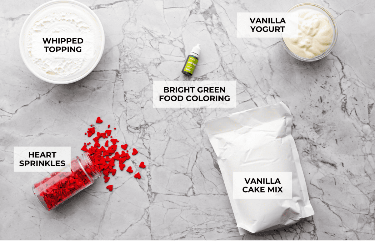 Grinch dip is a sweet and scrumptious dip perfect for any holiday party or gathering. It combines delicious cake mix, fluffy whipped topping, and smooth yogurt or pudding to create a fun dip for cookies, treats, or fruit. Overhead shot of labeled ingredients.