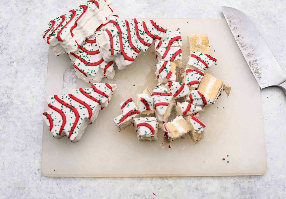 Little Debbie Christmas tree trifle is super adorable and tastes amazing! It's filled with sweet strawberries, creamy cream cheese, whipped topping flavored fluff, and chunks of the iconic Little Debbie Christmas trees. Overhead shot of cut up Christmas tree cakes.