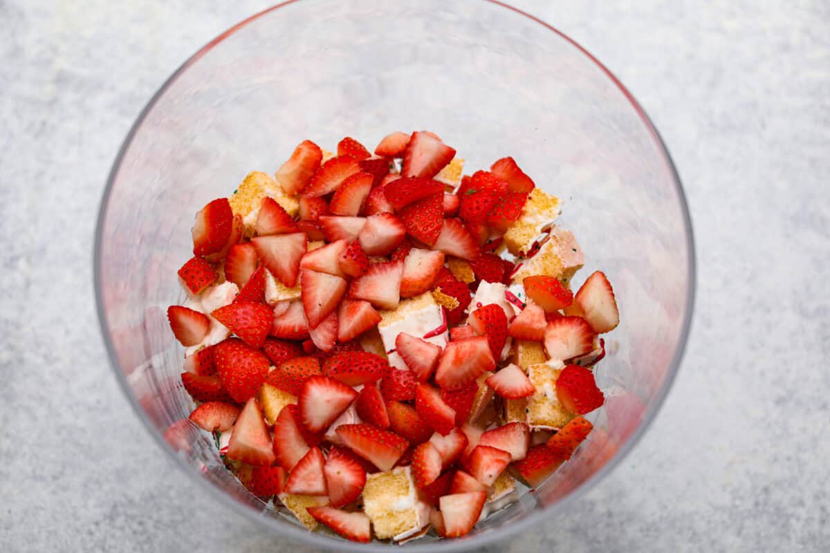 Little Debbie Christmas tree trifle is super adorable and tastes amazing! It's filled with sweet strawberries, creamy cream cheese, whipped topping flavored fluff, and chunks of the iconic Little Debbie Christmas trees. Overhead shot of fresh strawberries on top of the Christmas cake chunks.