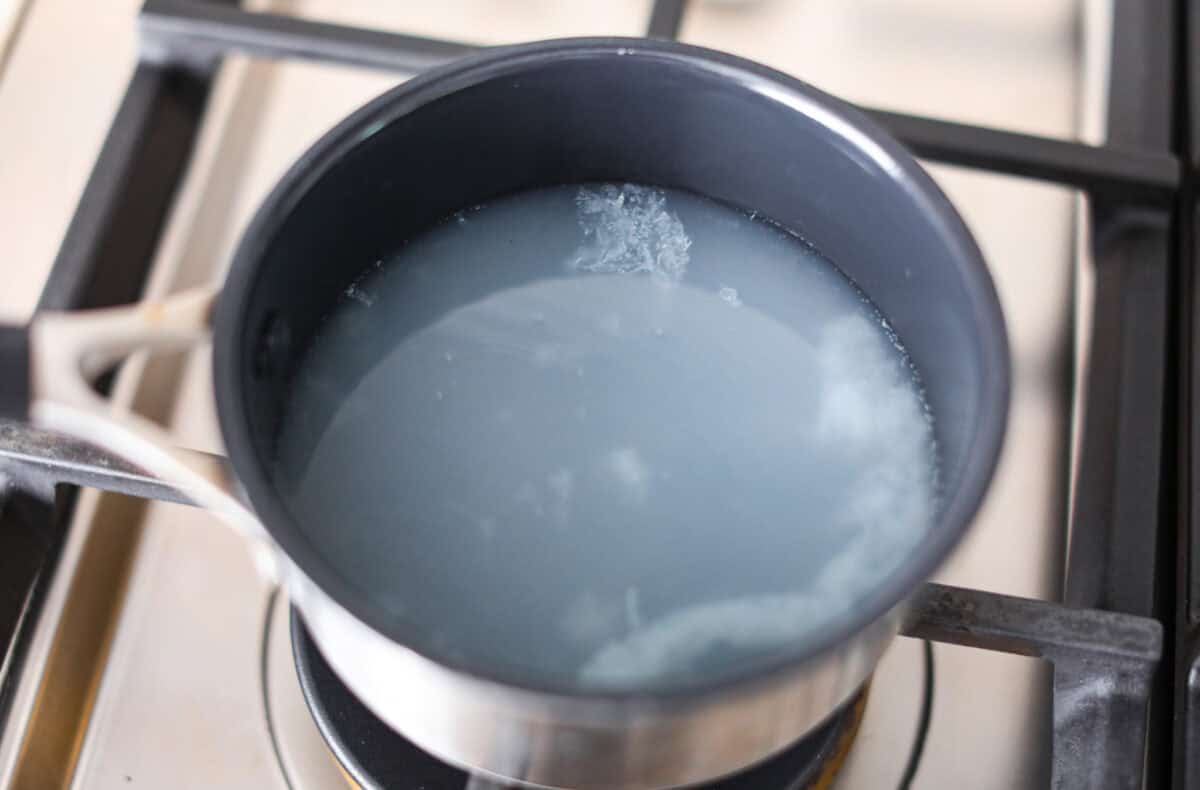 Whenever I am sick, the Starbucks Medicine Ball is my go-to, and this homemade version is even better! Perfect for cold and flu season, this warm drink made of lemonade, honey, and tea is soothing and delicious! Overhead shot of lemonade in a pot on the stovetop.