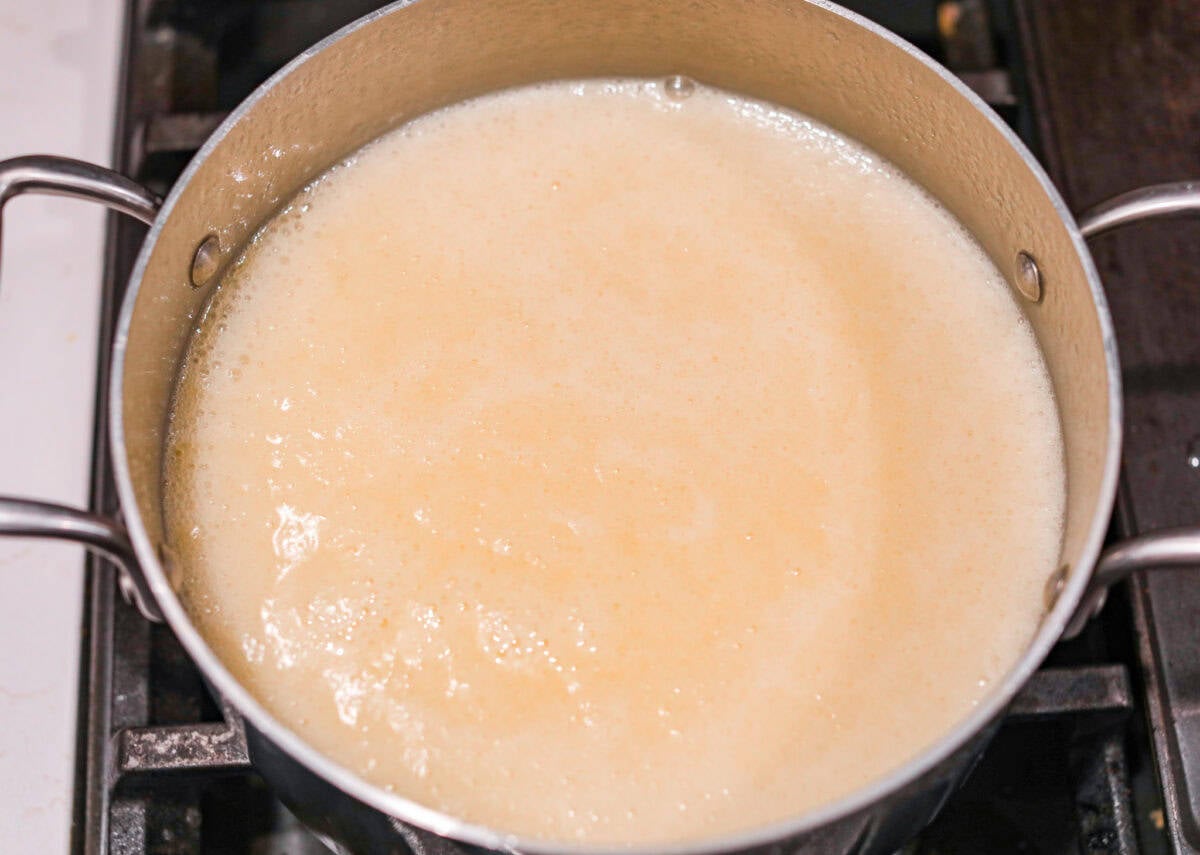 the sugar, butter, salt, and evaporated milk Overhead shot of the sugar, butter, salt, and evaporated milk being heated on the stove to a rolling boil.