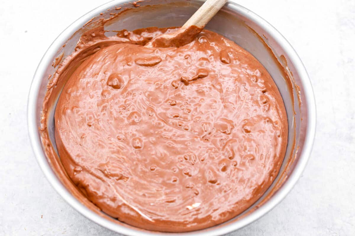 the sugar, butter, salt, and evaporated milk Overhead shot of someone stirring together the chocolate mixture with the warm milk mixture.