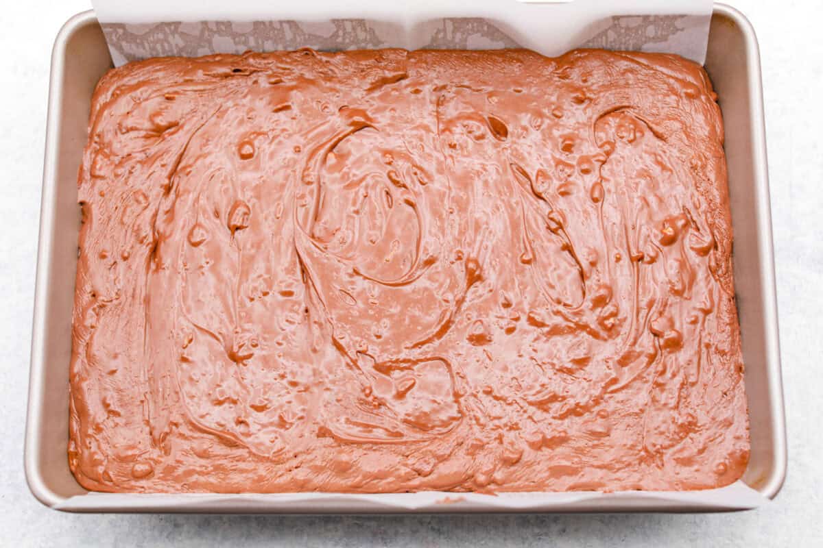 the sugar, butter, salt, and evaporated milk Overhead shot of the million dollar fudge mixture poured evenly into a pan with parchment paper.