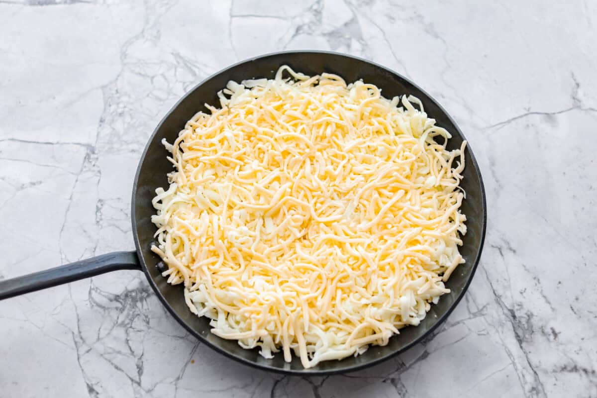 Queso Fundido is a delicious cheesy appetizer with a kick from the Mexican chorizo. It's loaded with buttery, melty cheeses and covered in spicy chorizo sausage. Overhead shot of cheese in a skillet.