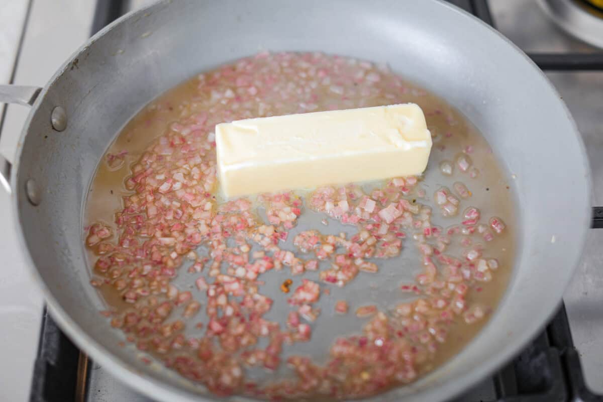 Rosemary Chicken is an incredibly simple yet flavorful dish you can whip up in no time. The infusion of butter with savory shallots, bright lemon juice, fresh rosemary, and tender seared chicken is an explosion of flavor. Overhead shot of shallots and juice with oil and butter.