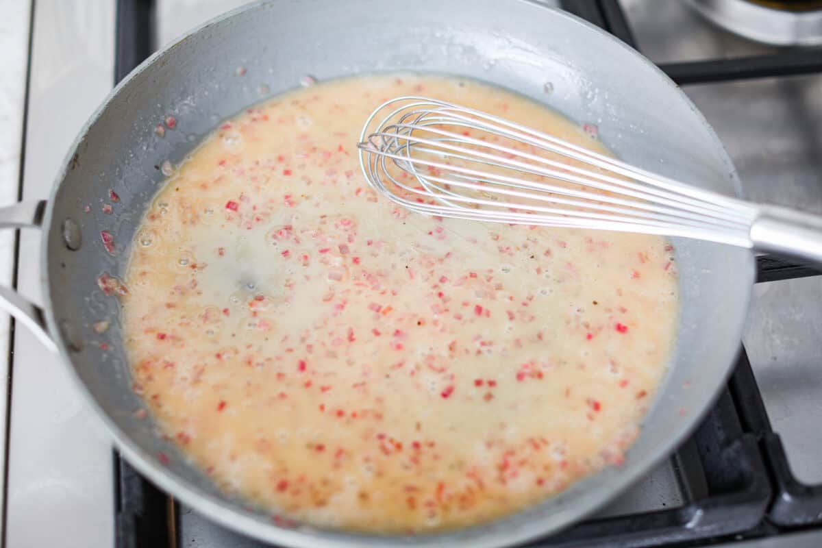 Rosemary Chicken is an incredibly simple yet flavorful dish you can whip up in no time. The infusion of butter with savory shallots, bright lemon juice, fresh rosemary, and tender seared chicken is an explosion of flavor. Overhead shot of rosemary chicken sauce simmering in a skillet.