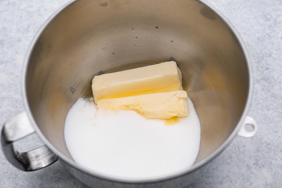 Tom Cruise coconut cake is a dense pound cake with coconut flavor and silky white chocolate throughout. The indulgent frosting is a coconut cream cheese buttercream with sweetened coconut on the outside. It's a coconut lover's dream—but a super sweet one. Overhead shot of butter and sugar in a mixing bowl.