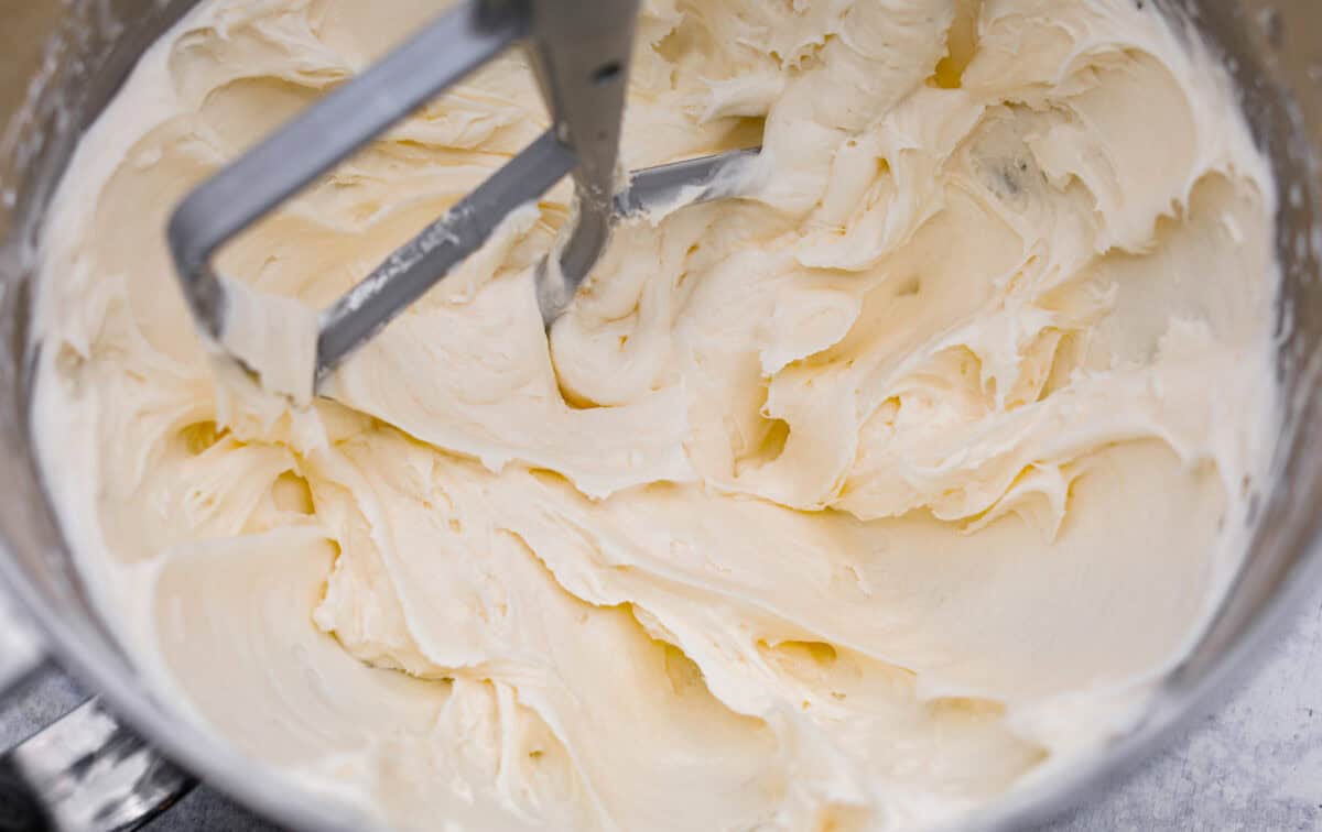 Tom Cruise coconut cake is a dense pound cake with coconut flavor and silky white chocolate throughout. The indulgent frosting is a coconut cream cheese buttercream with sweetened coconut on the outside. It's a coconut lover's dream—but a super sweet one. Overhead shot of the butter and sugar being beat in a mixing bowl.