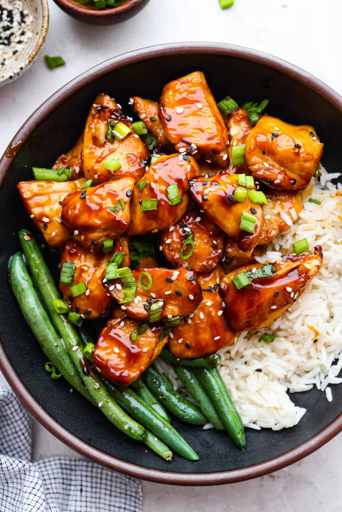Super flavorful Air Fryer Teriyaki Chicken cooks up perfectly every time! It's tender and juicy on the inside, with a tasty teriyaki sauce coating the outside. Pair with rice and veggies for an easy meal on busy nights! Overhead shot of plated air fryer teriyaki chicken next to green beans and rice.