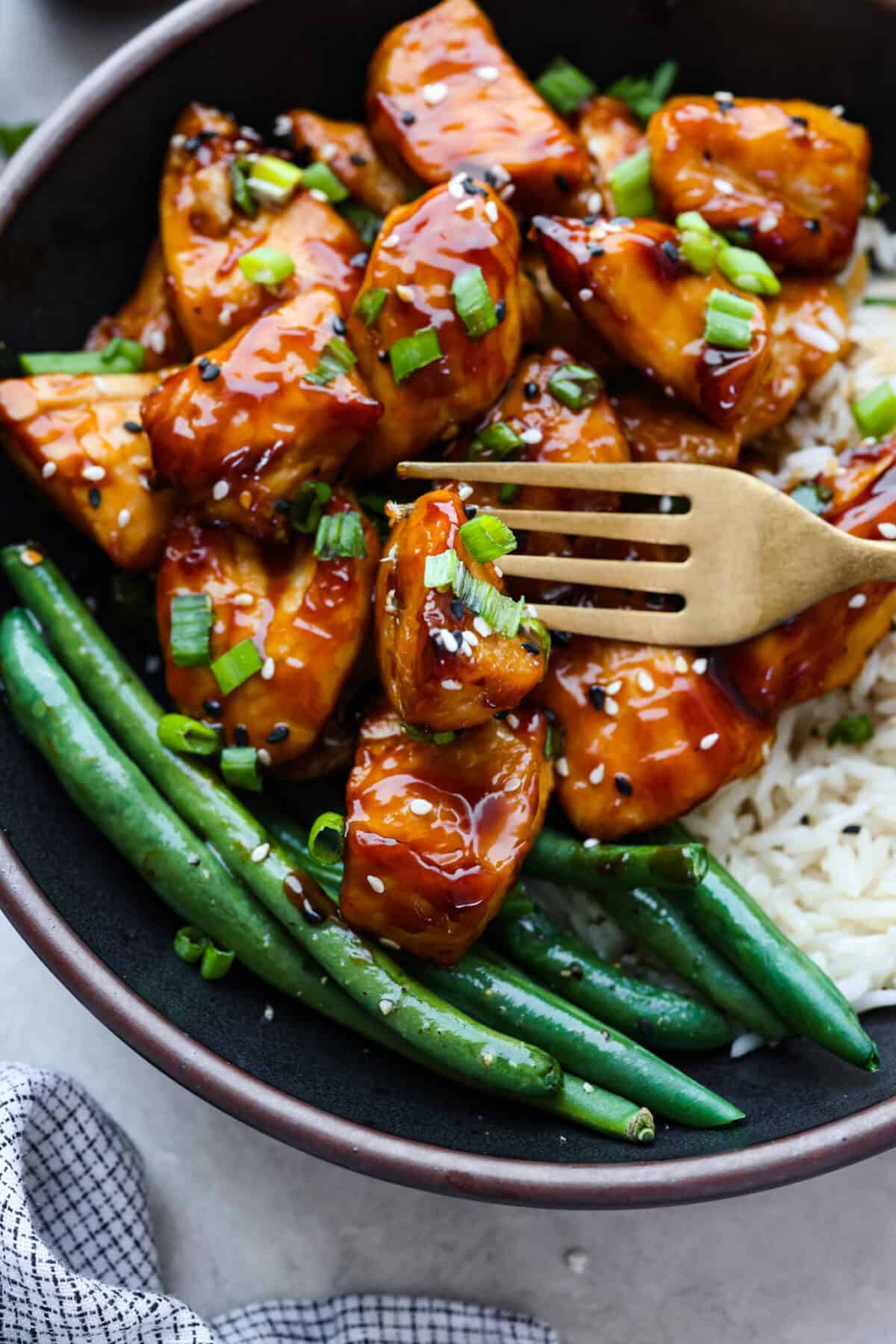 Super flavorful Air Fryer Teriyaki Chicken cooks up perfectly every time! It's tender and juicy on the inside, with a tasty teriyaki sauce coating the outside. Pair with rice and veggies for an easy meal on busy nights! Close up shot of plated air fryer teriyaki chicken.