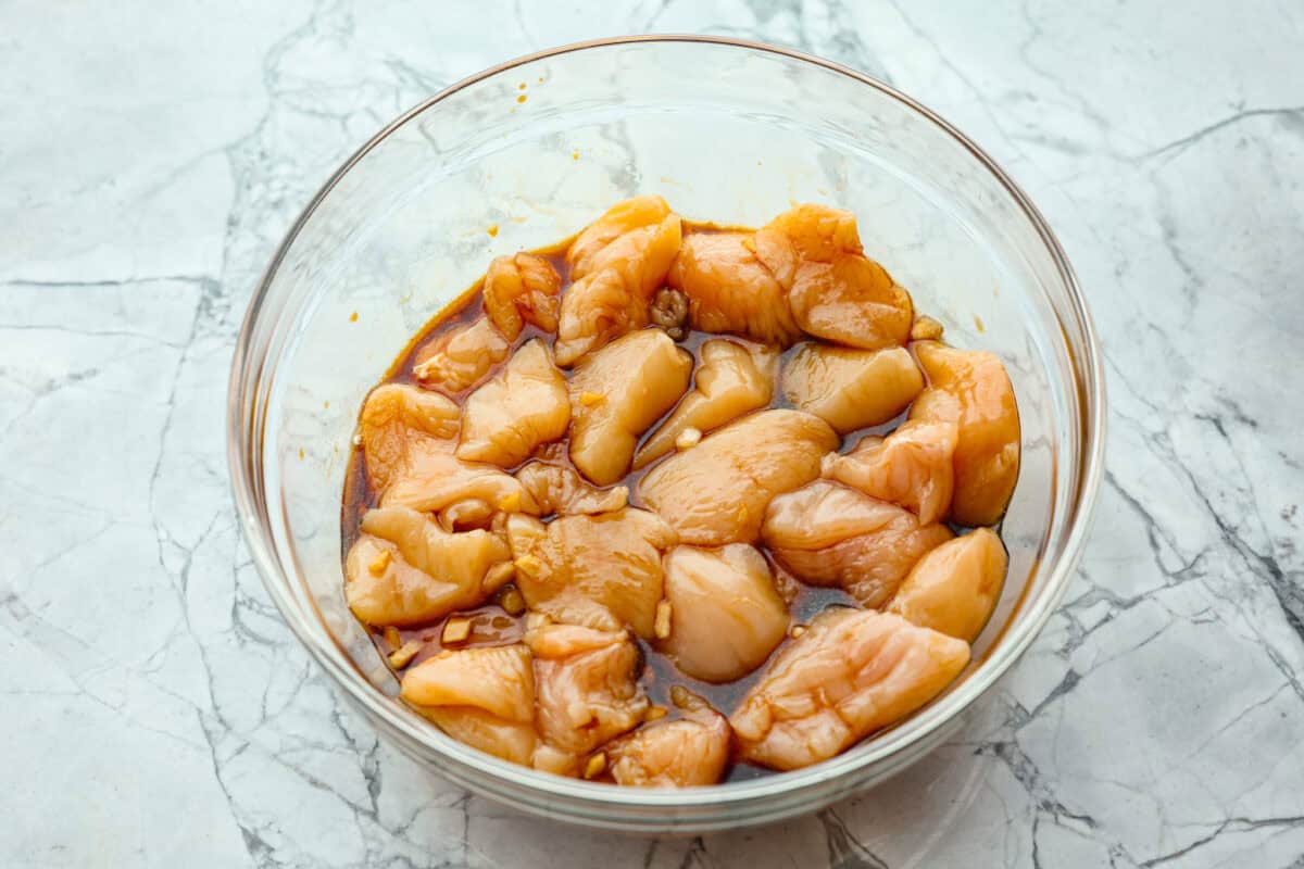 Super flavorful Air Fryer Teriyaki Chicken cooks up perfectly every time! It's tender and juicy on the inside, with a tasty teriyaki sauce coating the outside. Pair with rice and veggies for an easy meal on busy nights! Overhead shot of raw chicken pieces in marinade.