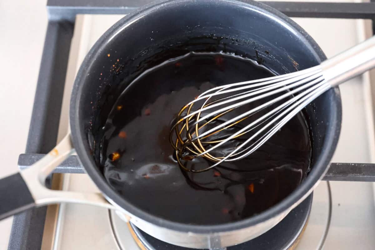 Super flavorful Air Fryer Teriyaki Chicken cooks up perfectly every time! It's tender and juicy on the inside, with a tasty teriyaki sauce coating the outside. Pair with rice and veggies for an easy meal on busy nights! Overhead shot of sauce ingredients being whisked on the stove in a pot.