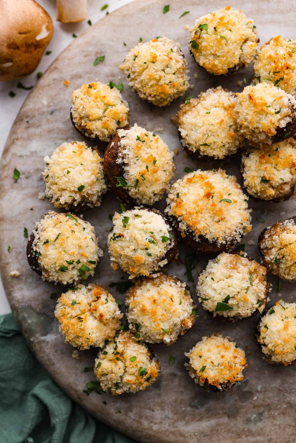 Boursin stuffed mushrooms are a fun, delicious appetizer or side dish. These creamy, cheesy stuffed mushrooms are packed with flavorful Boursin cheese and topped with a delightful breadcrumb crunch. Overhead shot of Boursin stuffed mushrooms on a serving platter.