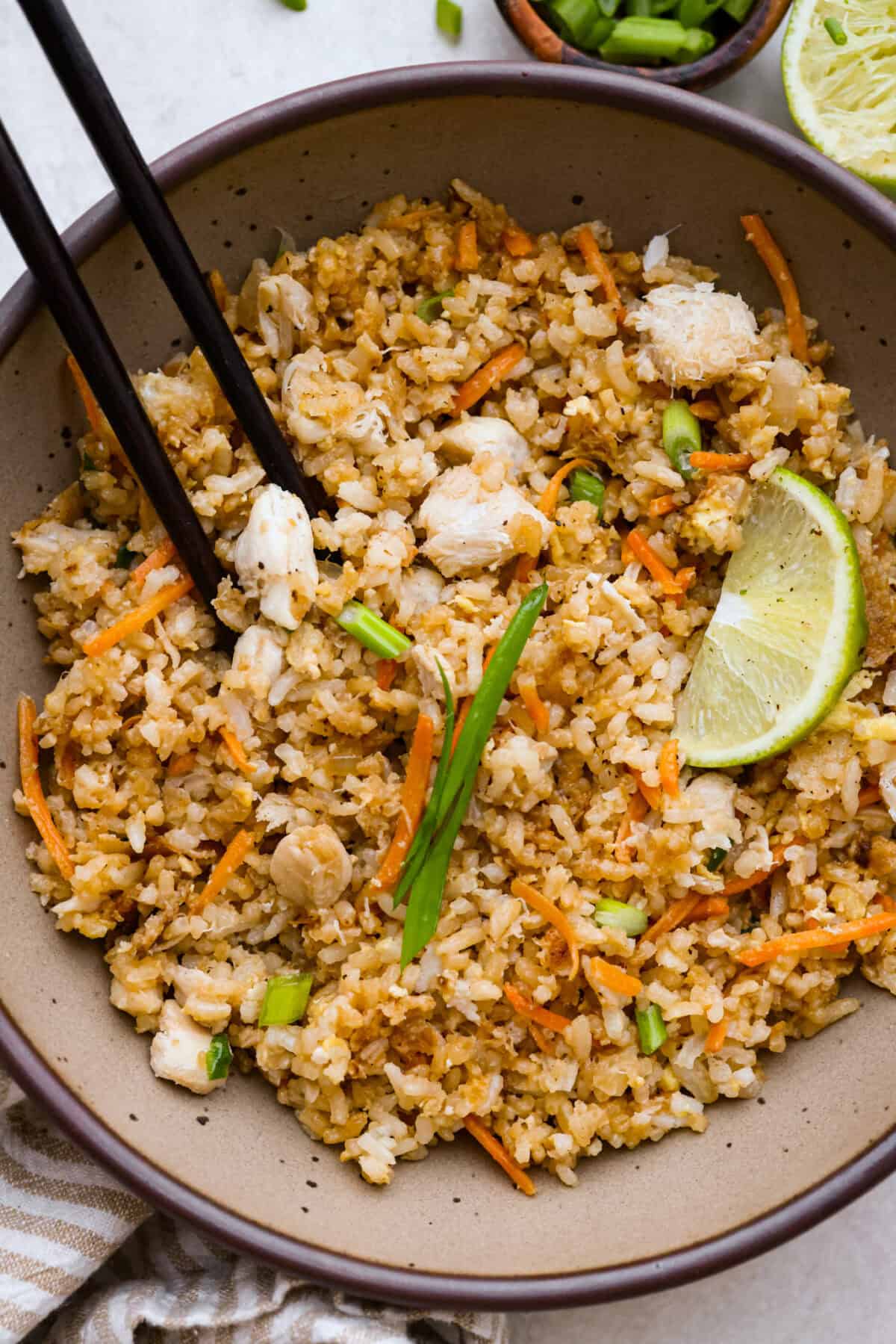 Delicious crab fried rice comes together in just 25 minutes with simple ingredients and tons of flavor! It combines the sweetness of lump crab meat with the savory flavors of classic fried rice for an endlessly satisfying dish that's sure to become a family favorite! Overhead shot of a bowl of crab fried rice.