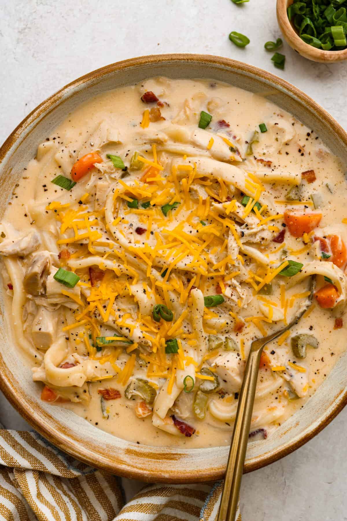 This crack chicken noodle soup is absolutely irresistible! It's packed with shredded chicken, bacon, ranch seasonings, and noodles, all in a deliciously creamy broth. One bite, and you'll be hooked! Overhead shot of a bowl of crack chicken noodle soup.