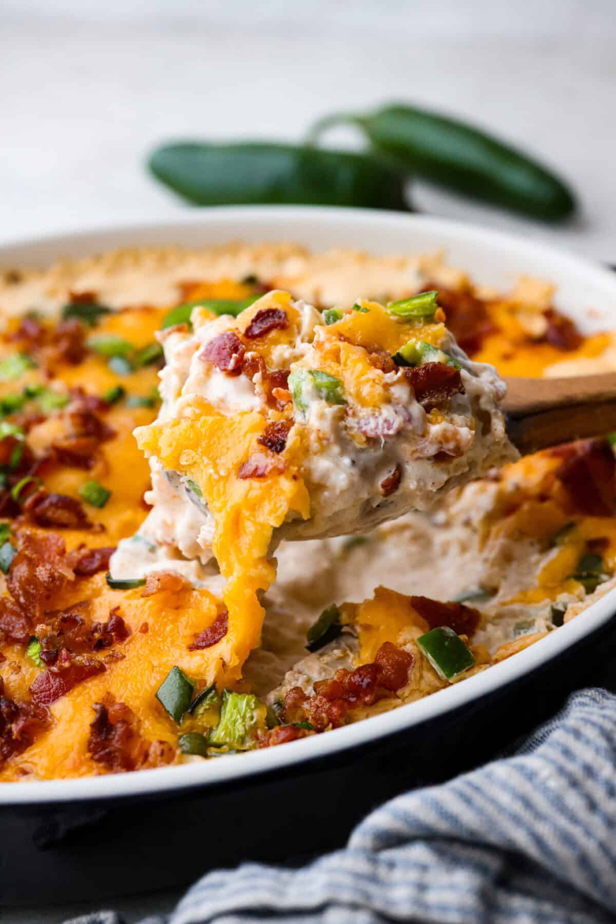 Spice up dinnertime with this creamy Jalapeño Popper Casserole! Packed with tender chicken, melty cheese, and just the right kick of heat, it's hearty and so easy to make. Delicious comfort food with a spicy twist! Close up shot of a scoop of Jalapeño popper casserole being lifted out of the baking dish.