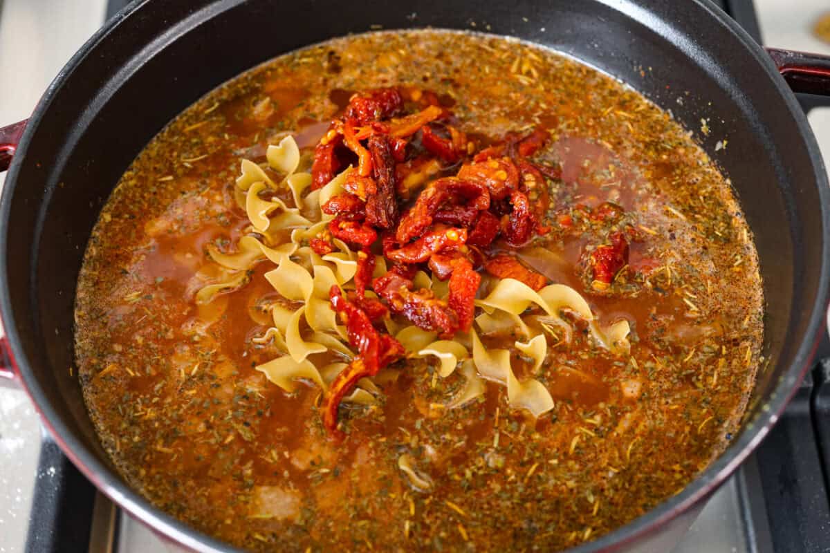 Fall in love with the creamy, comforting flavors in this marry me chicken soup! It's loaded with shredded chicken and tender noodles in a rich and creamy soup base. The irresistible flavors from the sun-dried tomatoes, garlic, and parmesan cheese take this soup over the top! Fourth photo of the noodles and sun-dried tomatoes added to the pot.