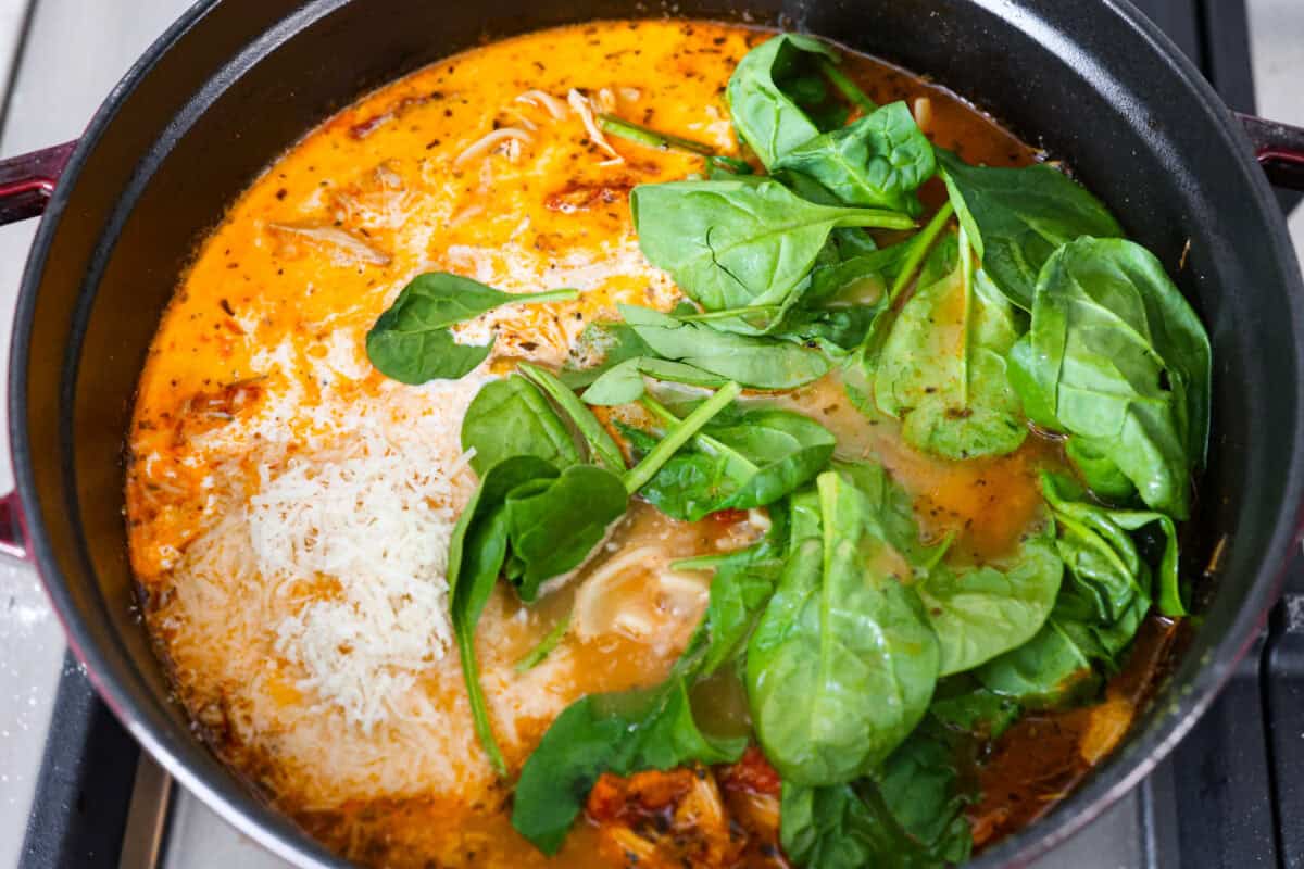 Fall in love with the creamy, comforting flavors in this marry me chicken soup! It's loaded with shredded chicken and tender noodles in a rich and creamy soup base. The irresistible flavors from the sun-dried tomatoes, garlic, and parmesan cheese take this soup over the top! Fifth photo of the cheese, cream, and spinach added to the pot.