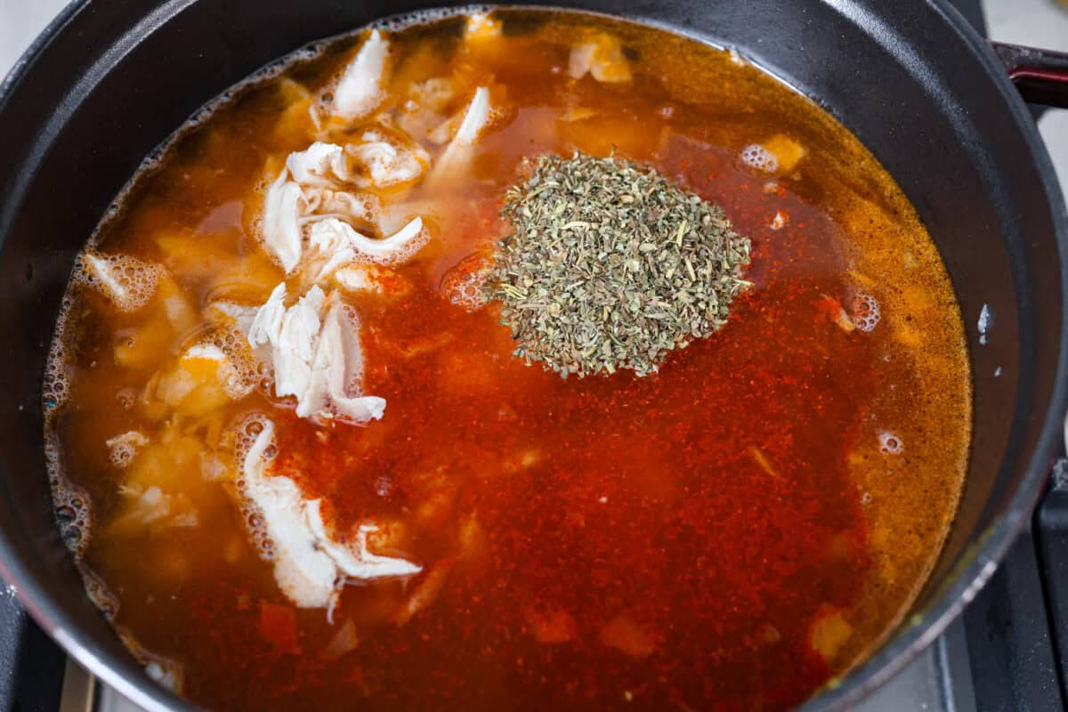 Fall in love with the creamy, comforting flavors in this marry me chicken soup! It's loaded with shredded chicken and tender noodles in a rich and creamy soup base. The irresistible flavors from the sun-dried tomatoes, garlic, and parmesan cheese take this soup over the top! Third photo of the broth, chicken, and seasonings added to the pot.