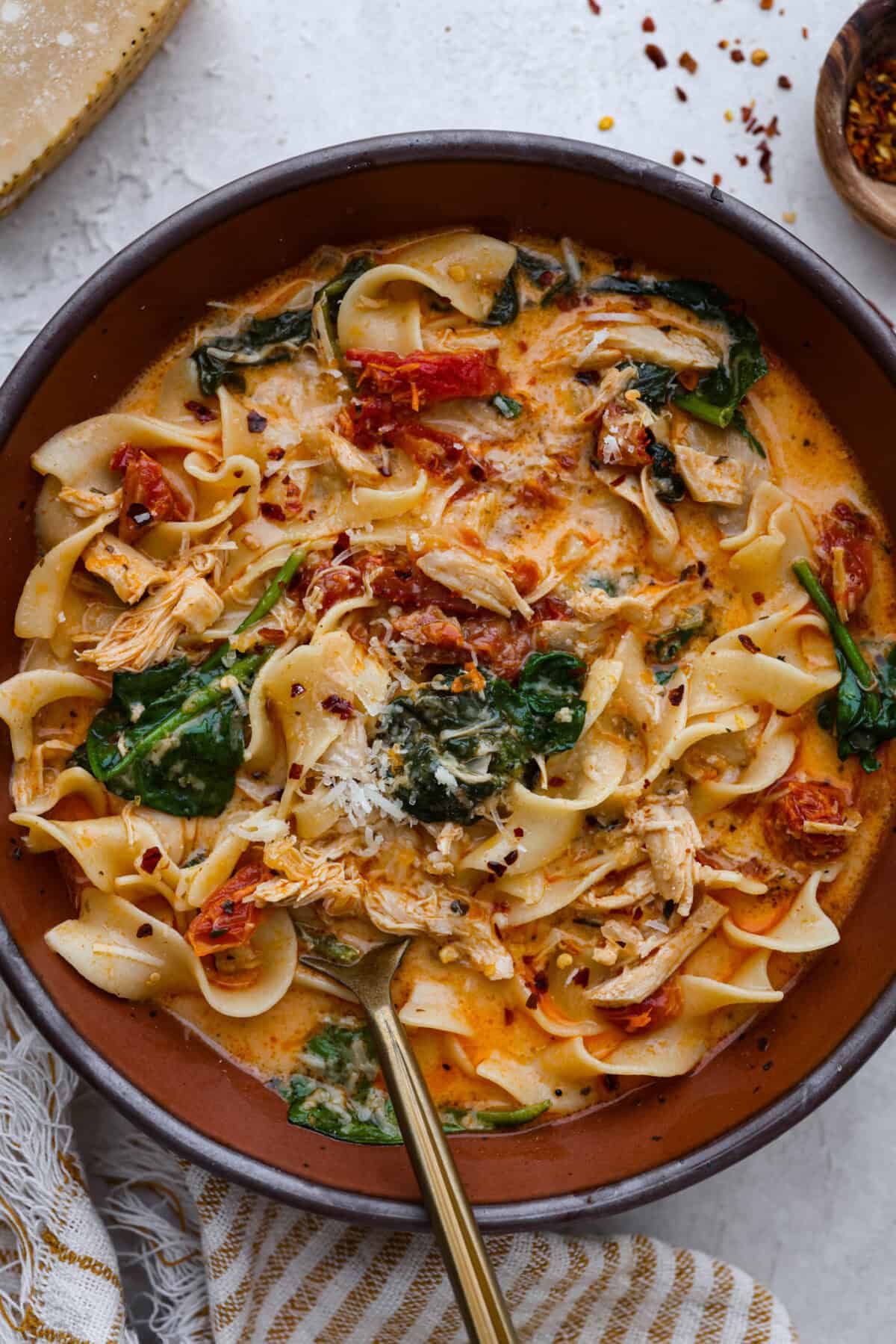 Fall in love with the creamy, comforting flavors in this marry me chicken soup! It's loaded with shredded chicken and tender noodles in a rich and creamy soup base. The irresistible flavors from the sun-dried tomatoes, garlic, and parmesan cheese take this soup over the top! Top close view of marry me chicken soup in a bowl.