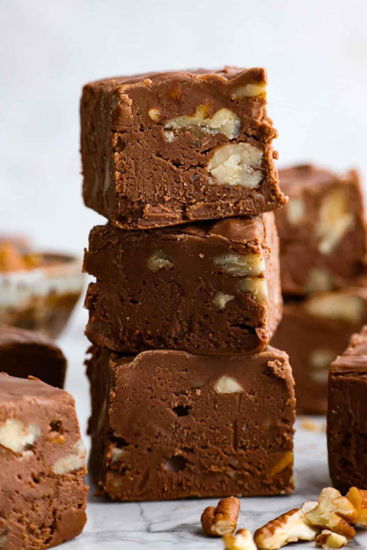 Million Dollar Fudge is a rich, creamy treat that lives up to its name! Packed with decadent chocolate, marshmallow fluff, and crunchy nuts, it’s perfect for gifting, sharing, or savoring all to yourself. Side shot of stacked pieces of million dollar fudge.