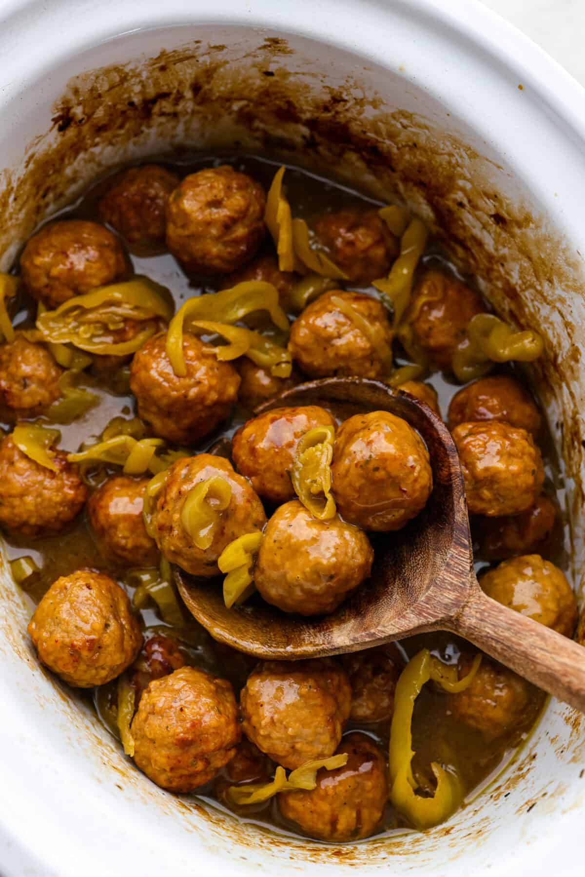 Crockpot Mississippi meatballs make the best little appetizer or side dish. The flavorful pepperoncini mixed with the au jus and ranch seasoning packets with delectable butter makes the most amazing sauce. It's perfectly soaked up by the tender meatballs. Overhead shot of crockpot Mississippi meatballs .