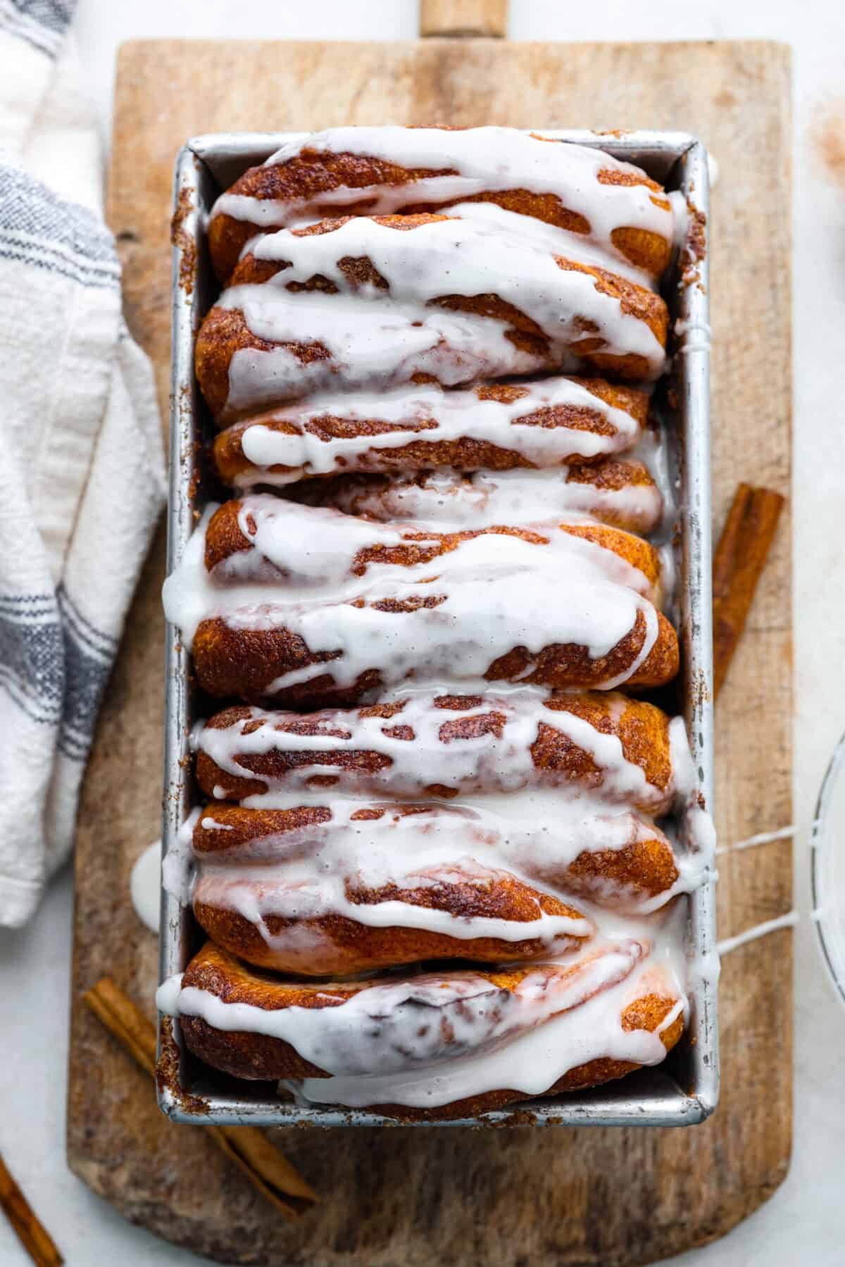 Irresistible Cinnamon Pull-Apart Bread is inspired by the popular cinnamon bread served at the Grist Mill eatery in Dollywood. With this copycat version, you can recreate that buttery, sweet deliciousness easily with frozen rolls. Overhead shot of the cinnamon pull-apart bread in the loaf pan with glaze drizzled over the top.
