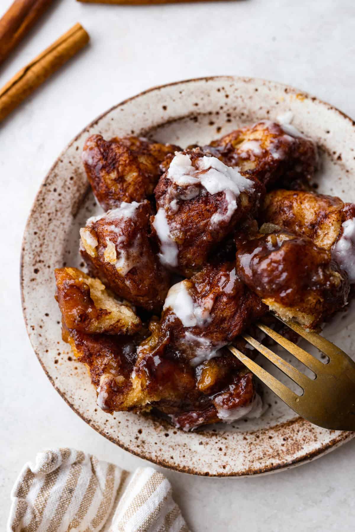 Crockpot monkey bread is an easy, gooey treat made in your slow cooker. It’s packed with soft biscuit pieces, cinnamon-sugar flavor, and a sweet buttery glaze. No oven needed! Overhead shot of plated crockpot monkey bread pieces on a plate.