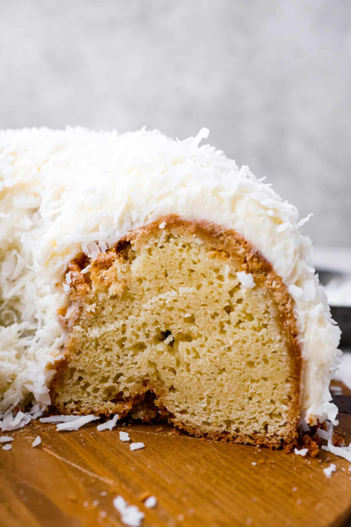 Tom Cruise coconut cake is a dense pound cake with coconut flavor and silky white chocolate throughout. The indulgent frosting is a coconut cream cheese buttercream with sweetened coconut on the outside. It's a coconut lover's dream—but a super sweet one. Side shot of the side of Tom Cruise coconut cake cut.