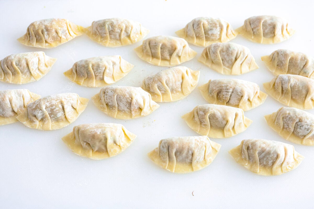 These vegetable dumplings are so full of Asian flavor, you won’t be able to stop at just one! Tender wontons are filled with an incredible veggie mixture that's infused with ginger, soy sauce, sesame oil and garlic. Like a potsticker without the meat! Angle shot of completed dumplings on a countertop.