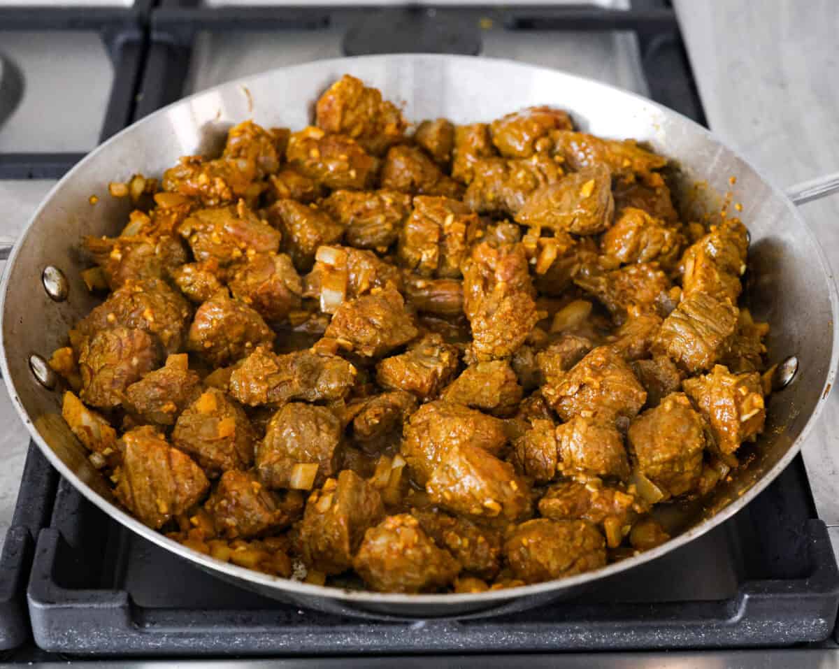 Comforting beef curry is a perfect blend of hearty and flavorful! With its mild spice level, it’s a dish that everyone can enjoy, but you can easily turn up the heat with a pinch of red pepper. Pair it with rice or naan for the ultimate cozy dinner! Angel shot of the beef and onion mixture cooking in a skillet on the stove