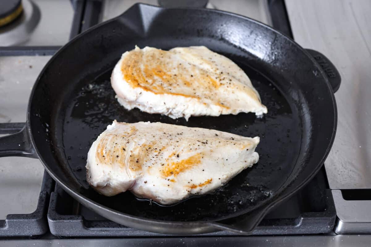 Chicken a la king is a timeless recipe that’s perfect for cozy dinners! This classic dish features tender chicken and veggies in a rich, creamy gravy-like sauce loaded with savory flavor. Angle shot of chicken breasts cooking on a skillet.