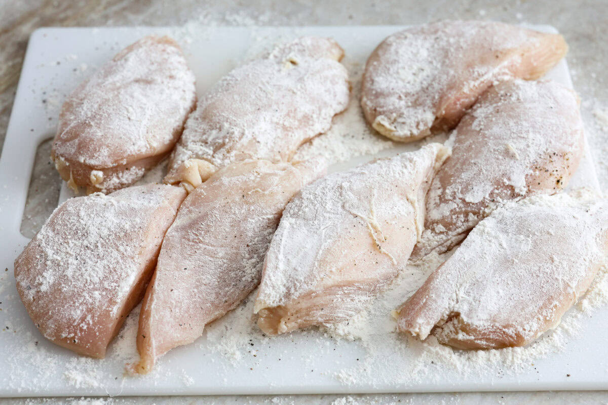 This Chicken Gloria is moist, perfectly baked chicken with a slightly seared crust. It cooks in a creamy sauce that is slightly tangy and full of flavor. It's topped with gooey cheese and makes a very satisfying meal! Overhead shot of chicken seasoned with salt and pepper and coated in flour.