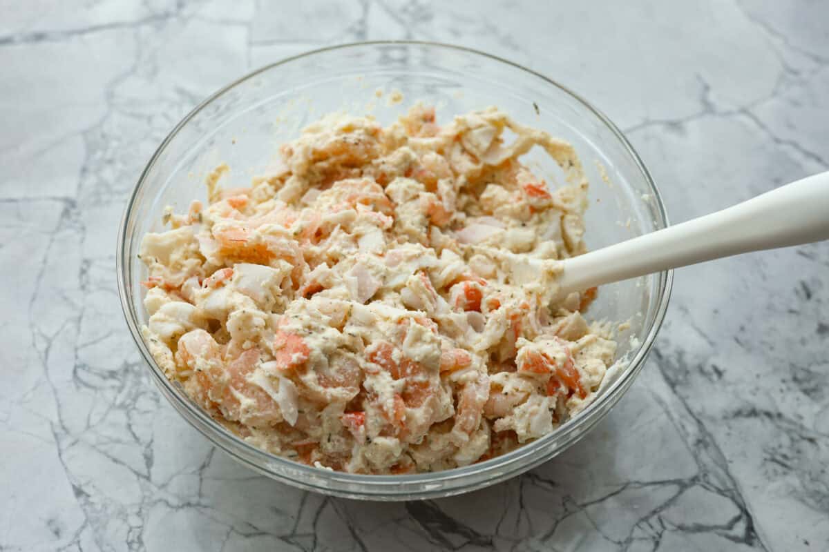 Seafood Stuffed Shells is a comforting meal that's sure to impress! Jumbo pasta shells are generously filled with a creamy, savory seafood filling and coated in a rich Alfredo-based sauce. Finish with a crispy crumb topping for an irresistible dinner! Overhead shot of filling ingredients mixed together in a bowl.