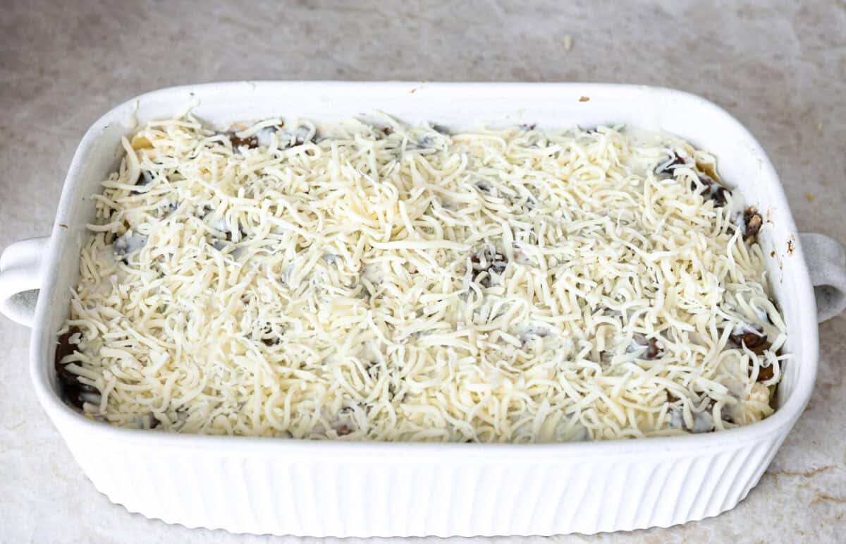 This creamy, cheesy mushroom lasagna is a delicious twist on the classic. Instead of traditional meat and red sauce, this recipe features layers of garlicky mushrooms and a rich bechamel sauce that brings incredible depth to every bite. Angle shot of the mushroom lasagna topped with cheese.